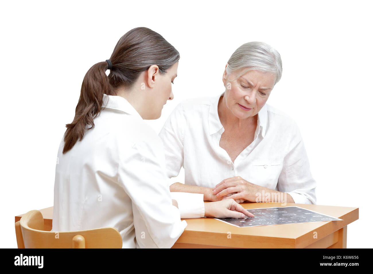 Mujeres de mediana edad que muestran su médico paciente senior una IRM de la cabeza, aislado sobre fondo blanco. Foto de stock