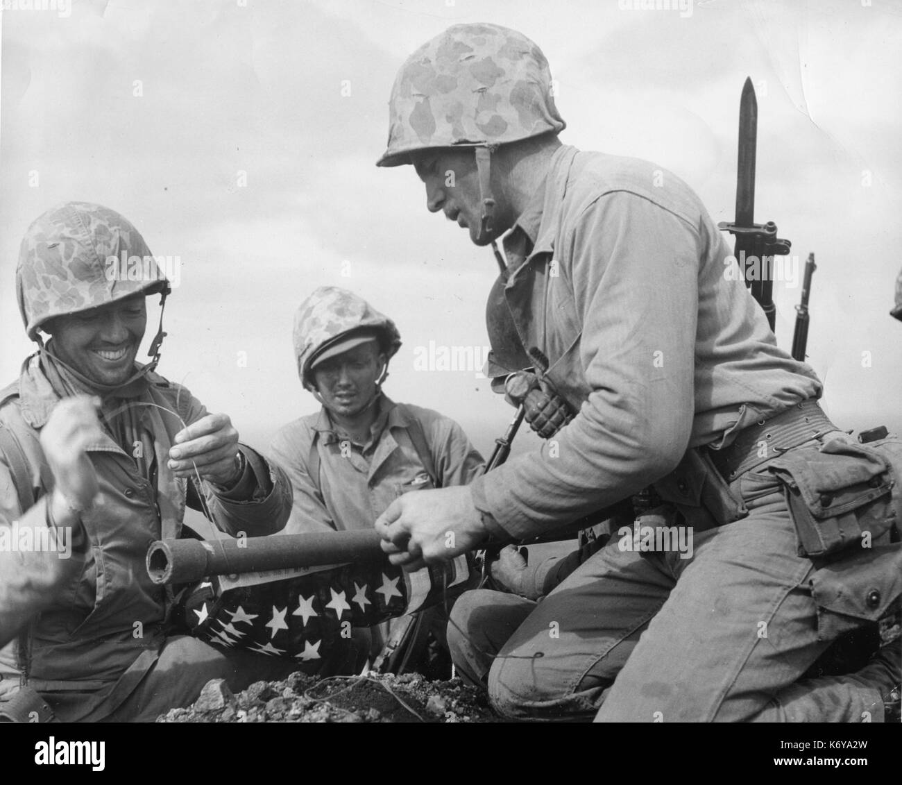 Tres infantes de marina de la 28ª Regimiento de la 5ª División de Infantería de Marina llevaron su bandera americana a la cima del monte Suribachi en Iwo Jima, y mientras todavía la batalla rabió sobre otras partes de la isla, manchada de sangre que izada desafiantemente vieja gloria en el rostro del enemigo. Iwo Jima, 23 de febrero de 1945. Foto por Lou Lowery. Foto de stock