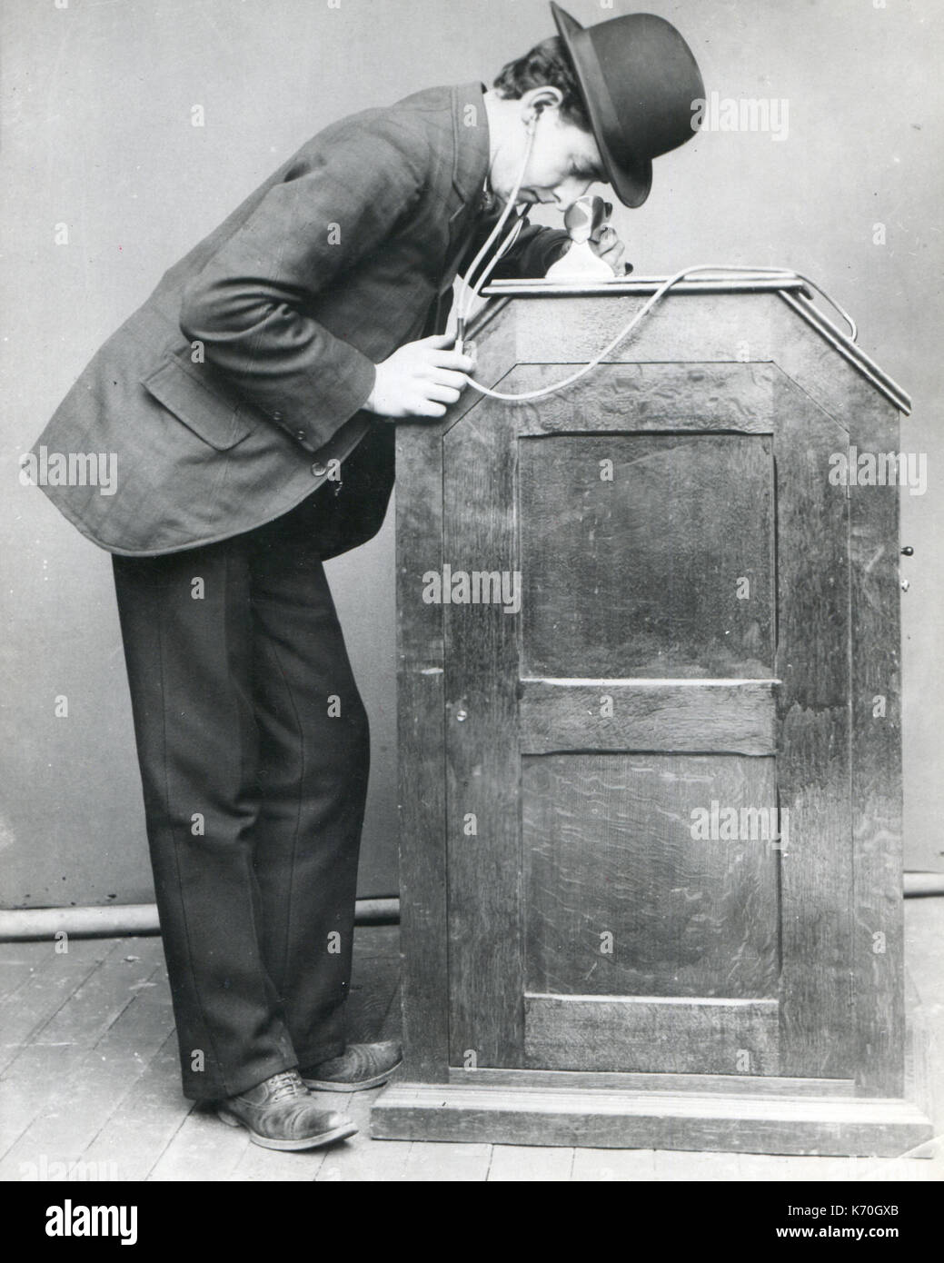 Nueva York - un hombre que busca en el Edison "peep-hole' Kinetoscope. Está equipado con tubos auditivos para sincronizarse con el sonido. Este fue el primer gran movimiento de la imagen mostrando la máquina. Foto de stock
