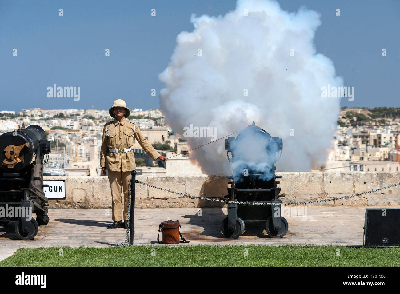 Un joven artillero dispara el cañón de mediodía de Malta para marcar la hora del mediodía. El mediodía cañonazos es una vieja tradición naval que fue restablecido en 2004 y OC Foto de stock