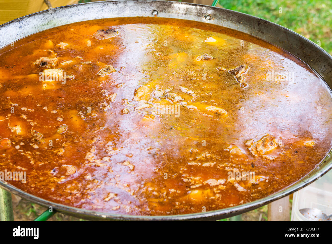 Proceso de cocinar paella valenciana o española jambalaya en sartén plana grande. Ingredientes carnes, arroz, legumbres, especias simmering en caldo con Foto de stock