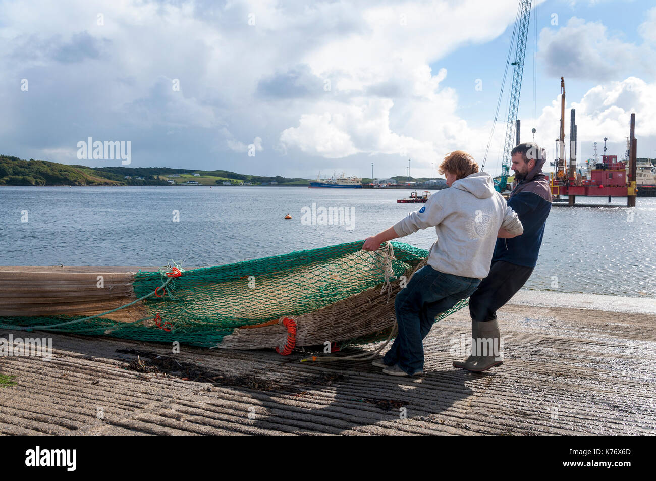 Killybegs, Condado de Donegal, Irlanda. Los pescadores de Irlanda del principal puerto pesquero aprovechar del sol para secar las redes agalleras en el quaysi Foto de stock