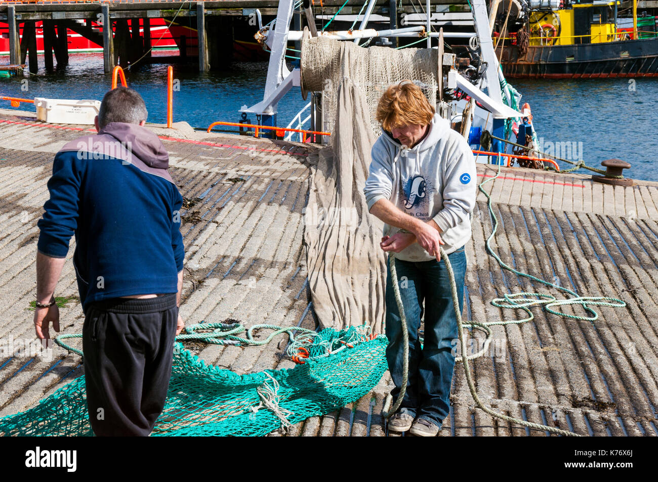 Killybegs, Condado de Donegal, Irlanda. Los pescadores de Irlanda del principal puerto pesquero aprovechar del sol para secar las redes agalleras en el quaysi Foto de stock