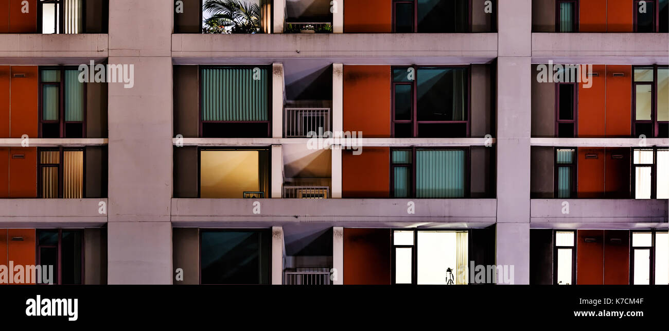 Ventanas de un departamento o condominio de gran altura edificio de noche visto desde afuera. Concepto de anonimato. Foto de stock
