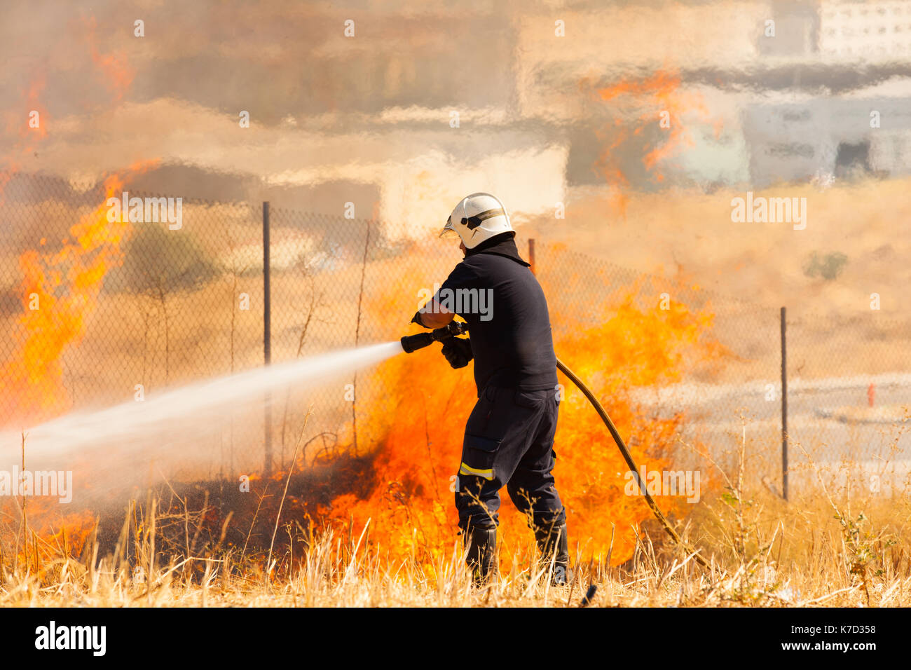 Bombero Apagando un incendio en la naturaleza con una manguera de agua  Fotografía de stock - Alamy