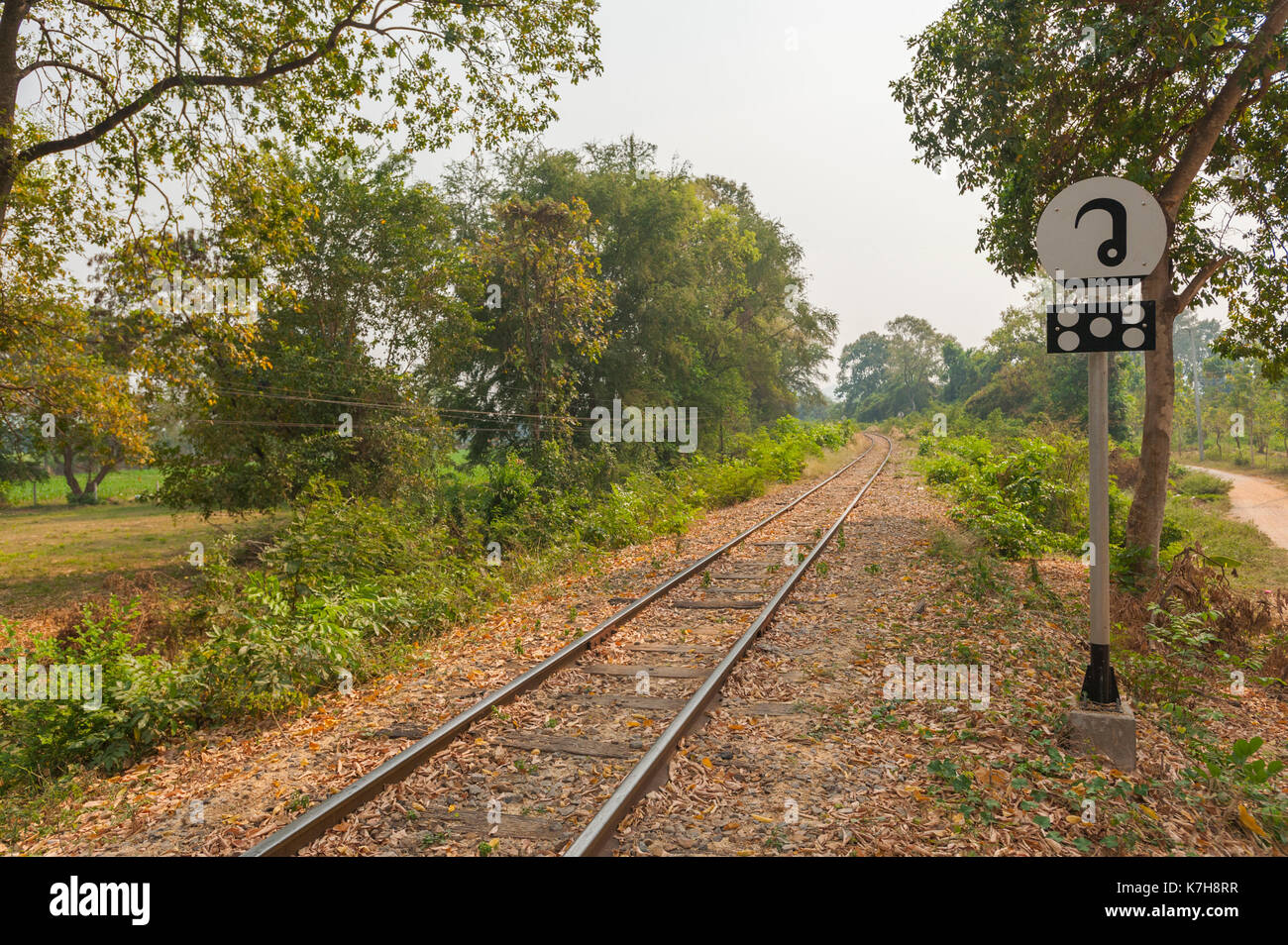Ferrocarril a través del campo con señal de información tailandesa en el extremo sur del puente del río Kwai. Kanchanaburi, Tailandia Foto de stock