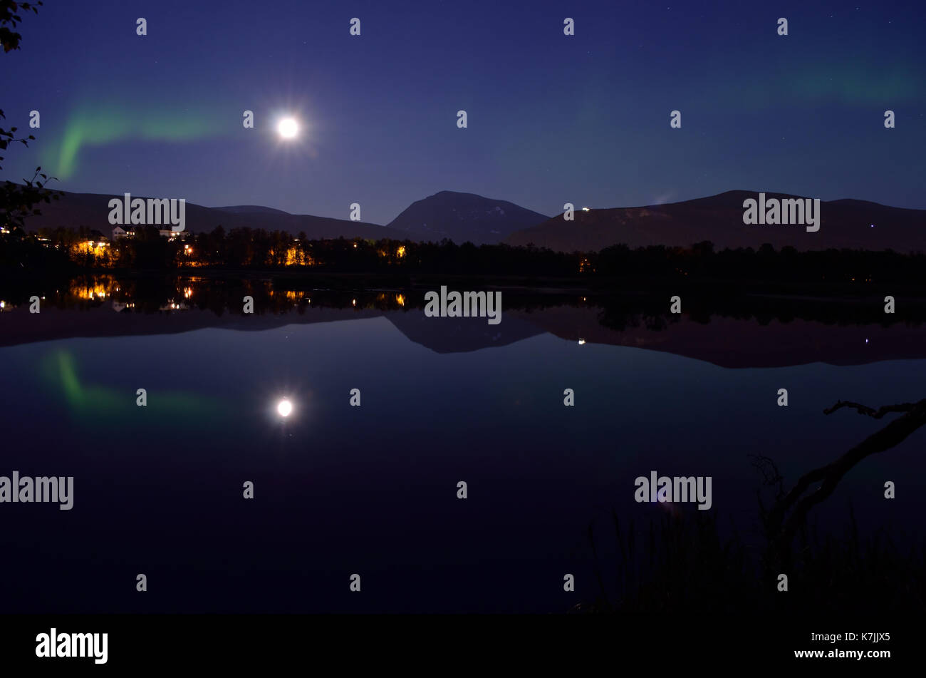 Majestuosa aurora borealis, Northern light más tranquilo lago espejo en la noche con edificios en el fondo Foto de stock