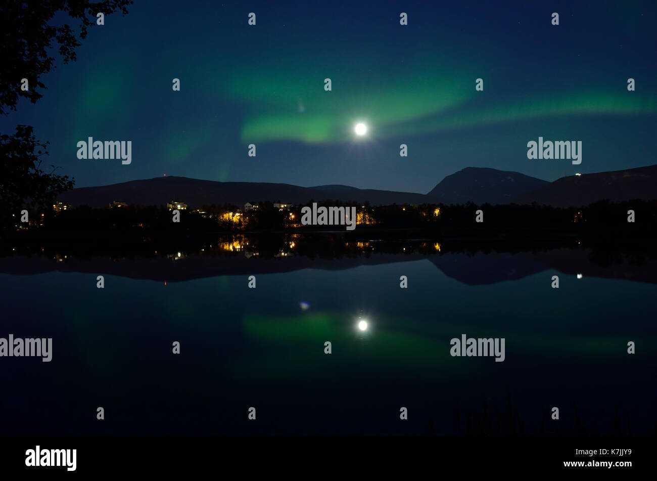 Majestuosa aurora borealis, Northern light más tranquilo lago espejo en la noche con edificios en el fondo Foto de stock