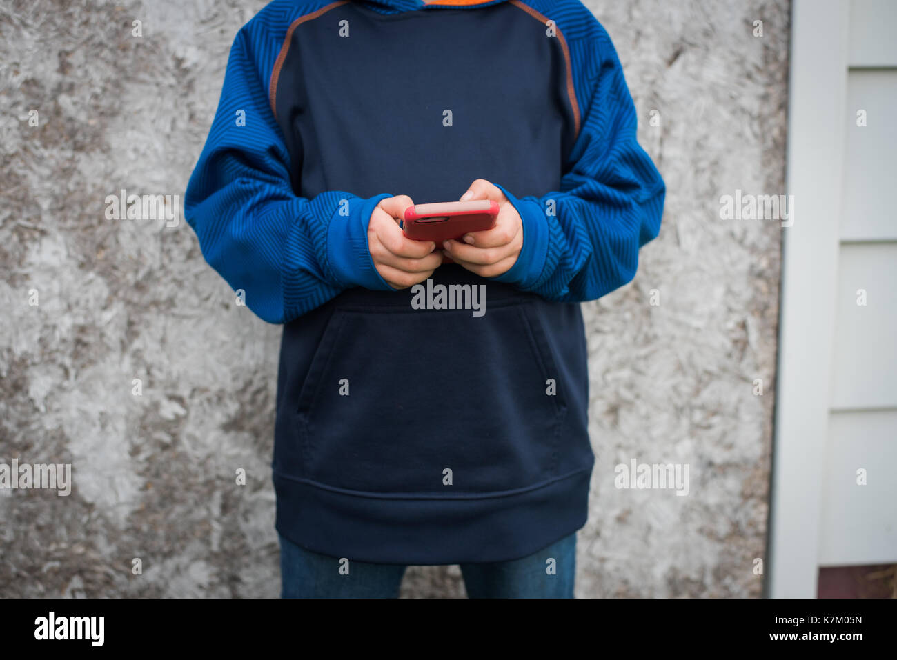 Un joven textos en un teléfono móvil. Foto de stock