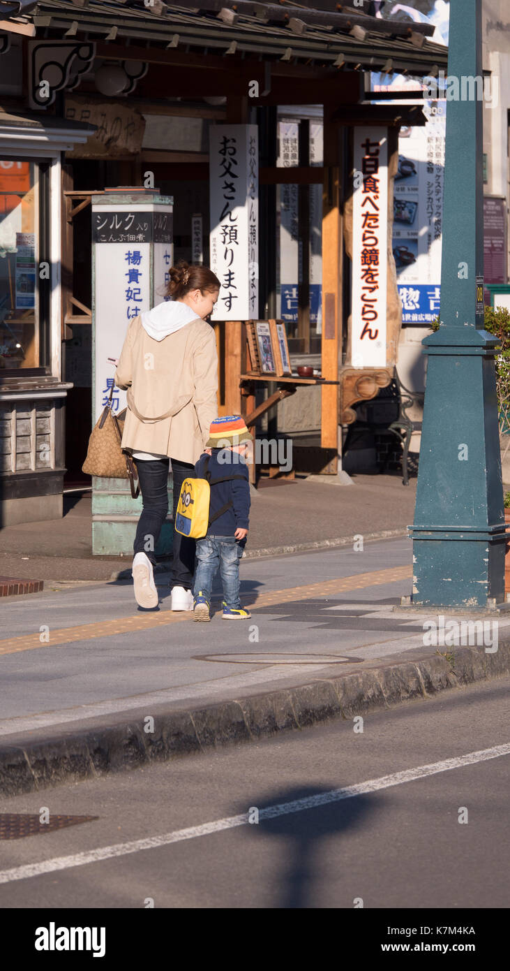 Pasear por los compradores tradicionales en Otaru escaparate de Japón. Edificio histórico de piedra con información turística signo delante del kanji de madera de color naranja. Foto de stock