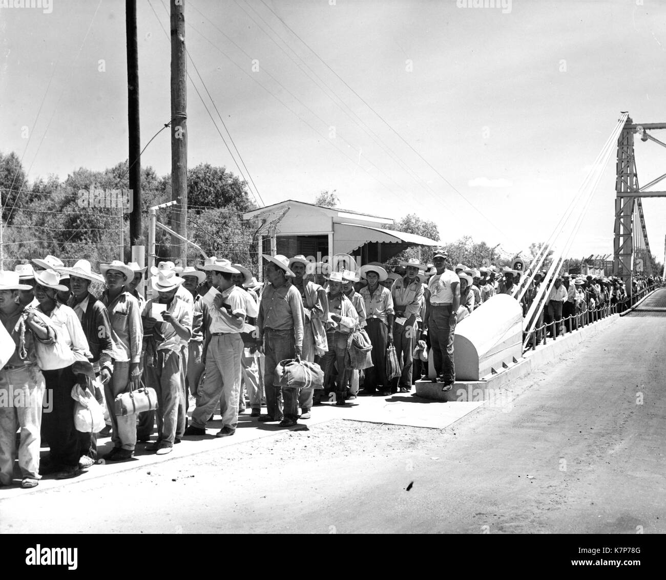 Trabajadores agrícolas mexicanos, más comúnmente conocido como braceros, line up para su procesamiento por parte de funcionarios de inmigración americana en el centro de trabajo, 01/01/1957. Foto de stock