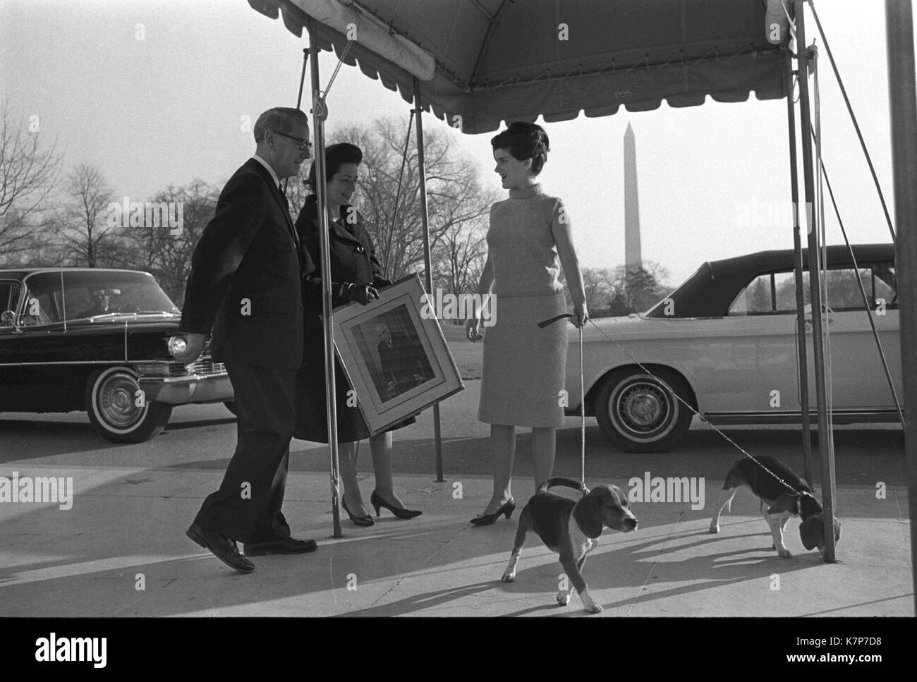 Lady Bird Johnson (centro) y su hija Luci Baines Johnson, sujetando las correas de los perros de la familia (derecha), son acompañados por la Casa Blanca usher J.B. Occidente como se muda a la Casa Blanca, en Washington, DC, 12/07/1963. Foto de stock