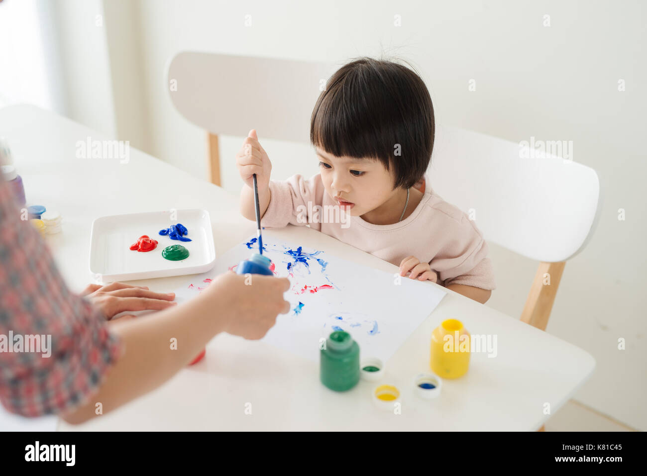 Una familia feliz es la pintura. La mamá ayudar a su hija el dibujo Foto de stock