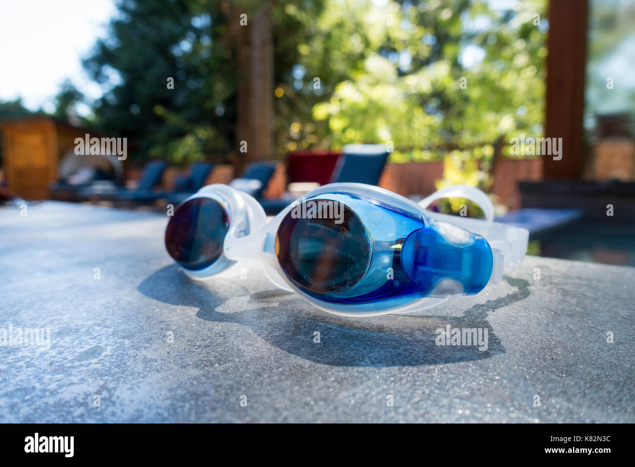 Primer plano de un par de gafas de natación en el borde de una piscina al aire libre Foto de stock