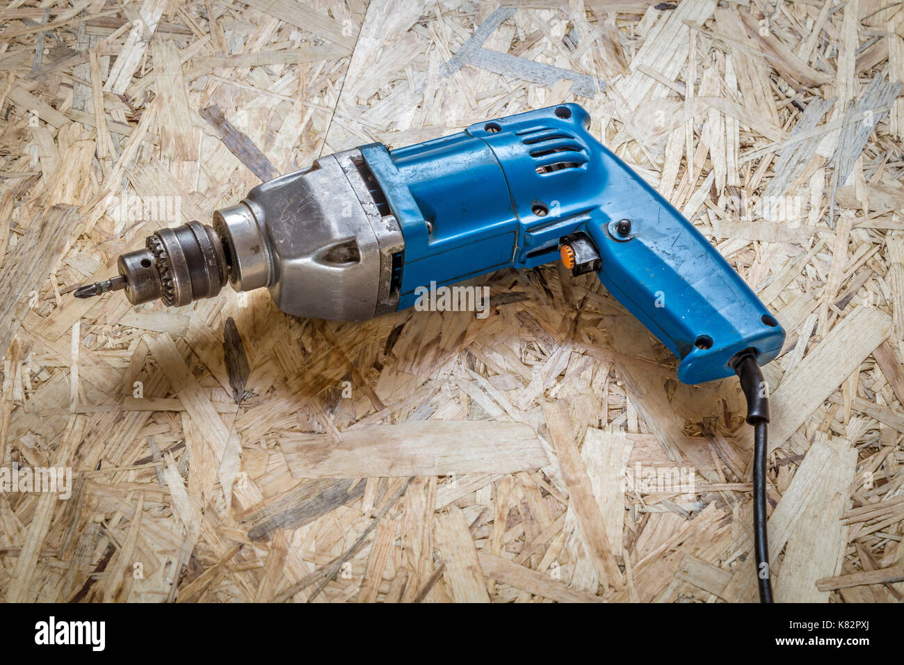 Casco azul-taladro destornillador cerca en una superficie de madera. Foto de stock