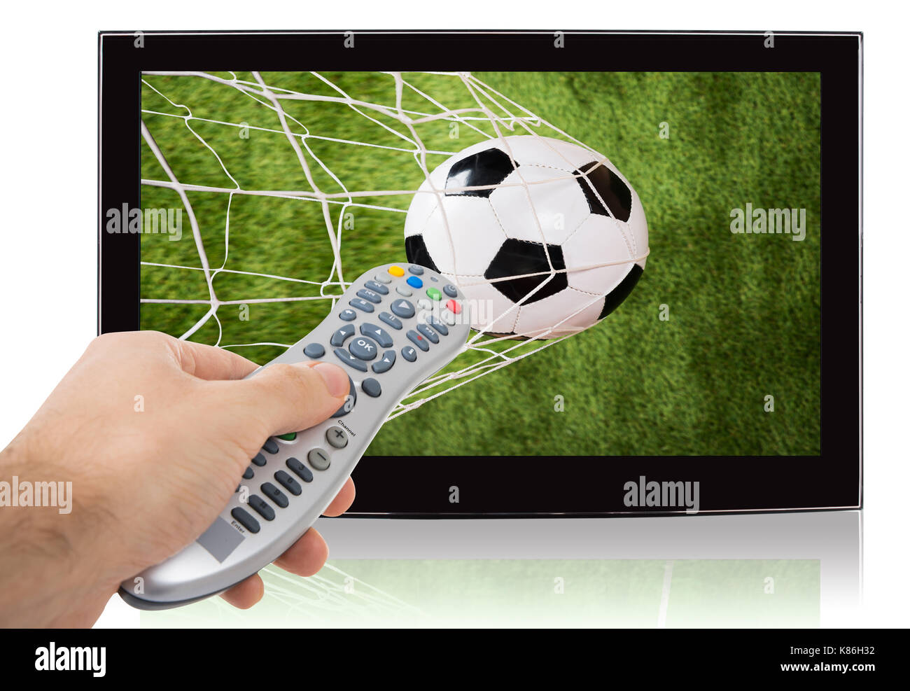 Mano mediante control remoto de ver el fútbol en televisión de pantalla plana contra el fondo blanco. Foto de stock