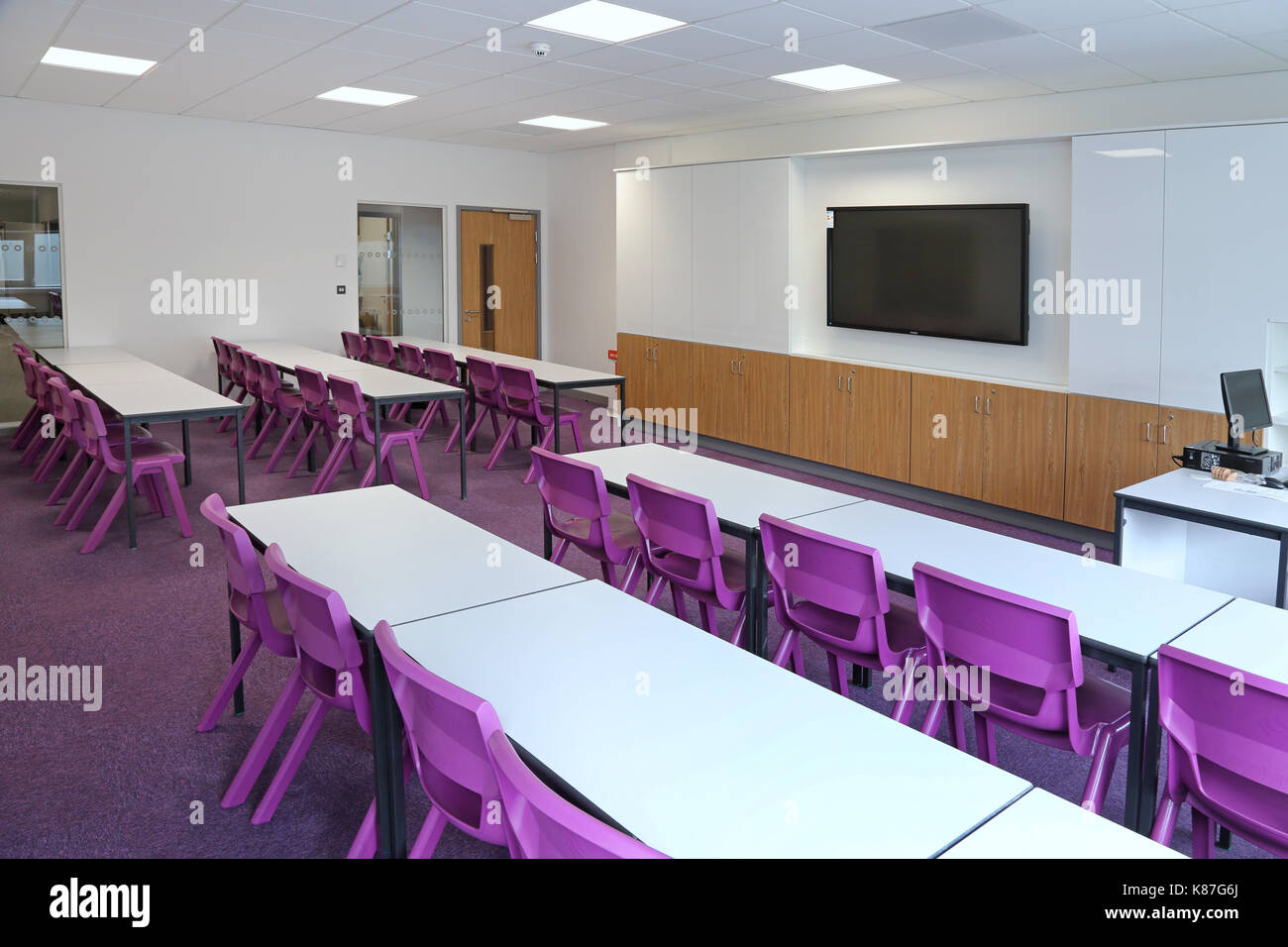 Un aula moderna en una nueva escuela secundaria de Londres. Muestra de diseño tradicional con escritorios frente a un monitor de un ordenador. Foto de stock