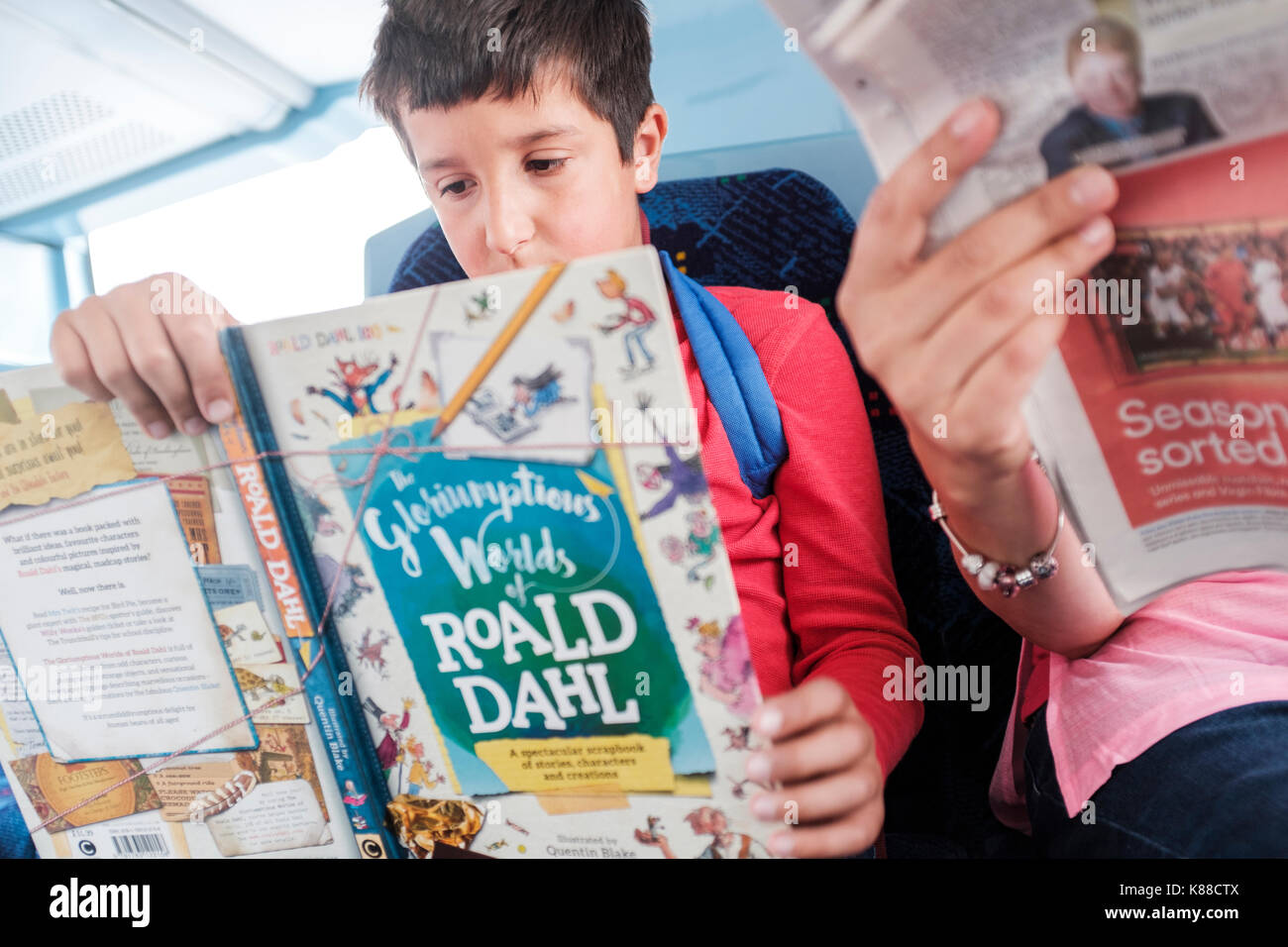 Vacaciones de verano días-boy,10,leyendo un libro en el autobús,Londres,Inglaterra Foto de stock