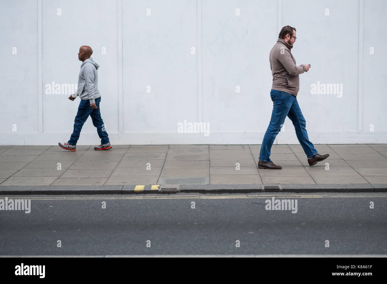 Dos hombres caminan en sentidos opuestos en Oxford Street de Londres, Reino Unido Foto de stock