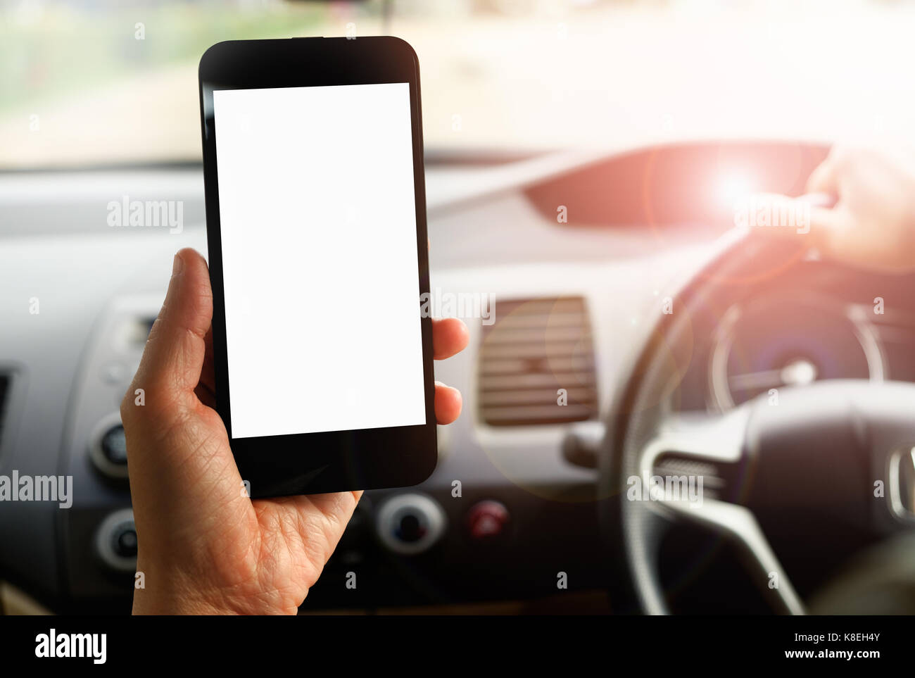 La mano es la celebración de un teléfono con pantalla táctil aislado en el coche. Foto de stock