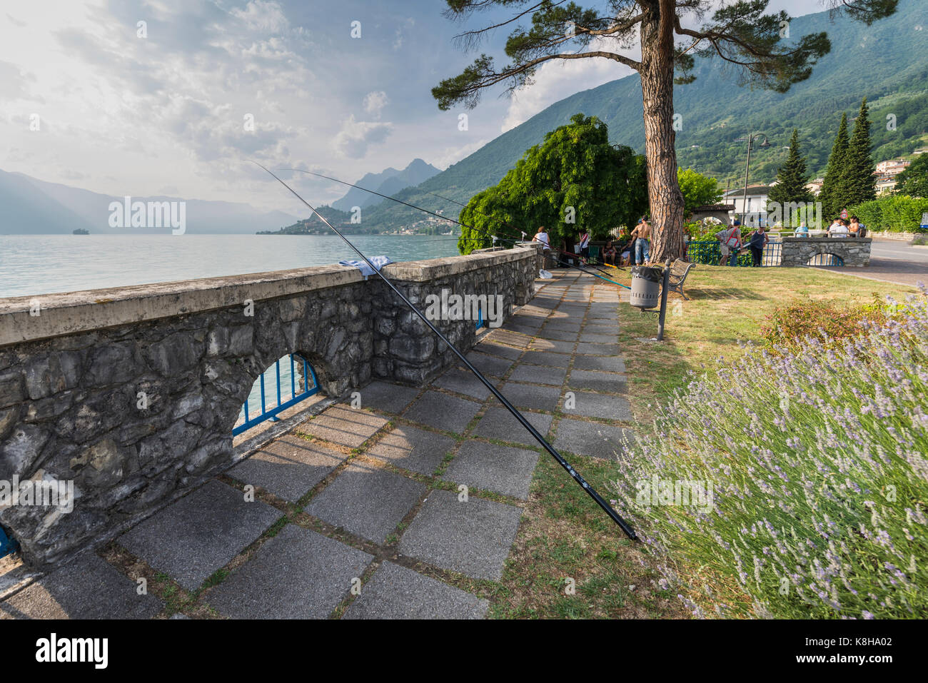 El Angler mit langen angelruten an der Mauer der seepromenade von venta marasinao am iseosee, lombardei, italien Foto de stock