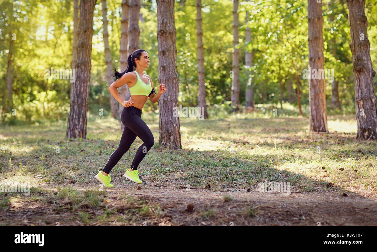 Una mujer corre por el bosque en una jog. Foto de stock