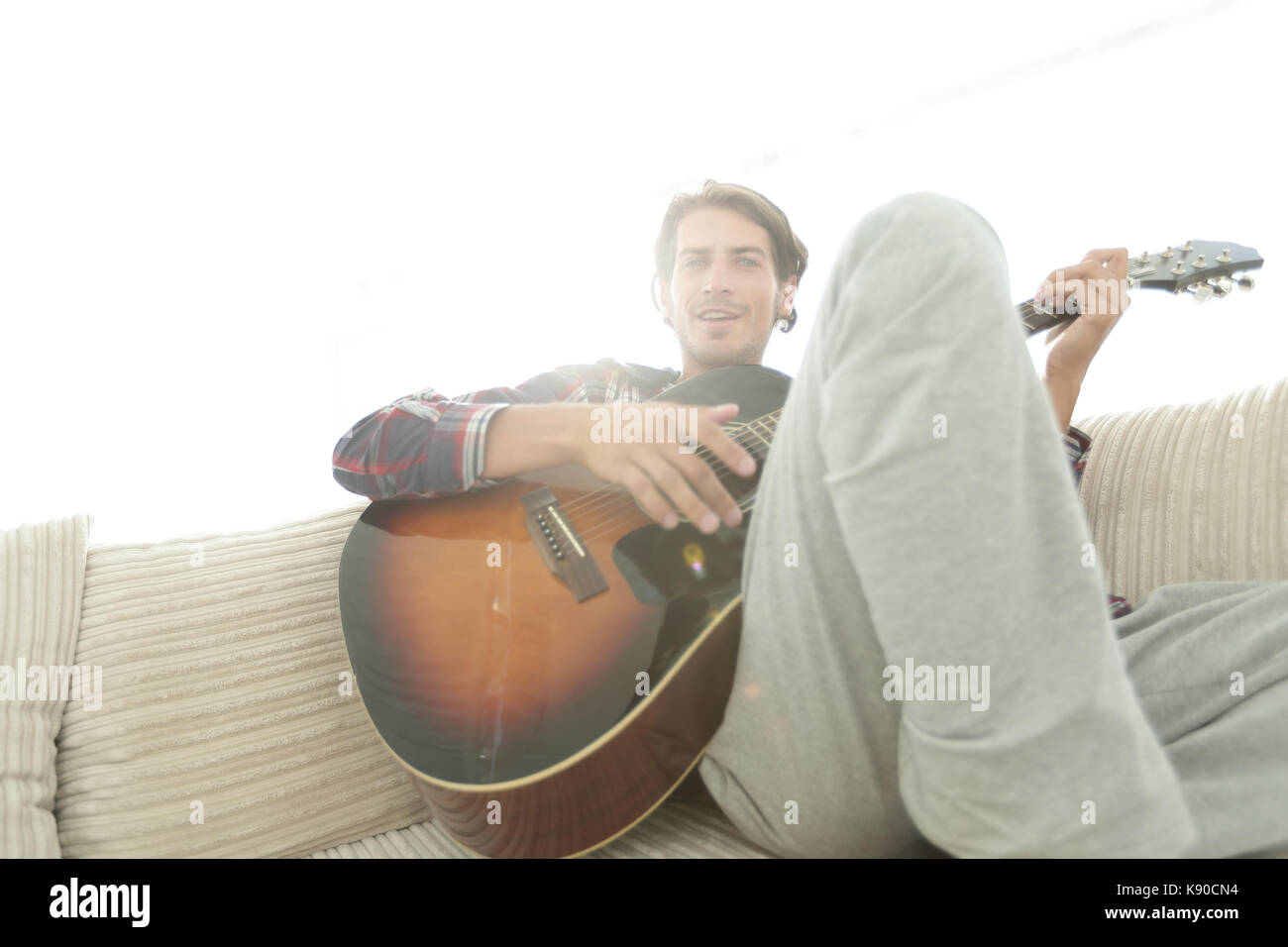 Hombre con Guitarra sentado en un sofá en el salón. El concepto de un estilo de vida Foto de stock