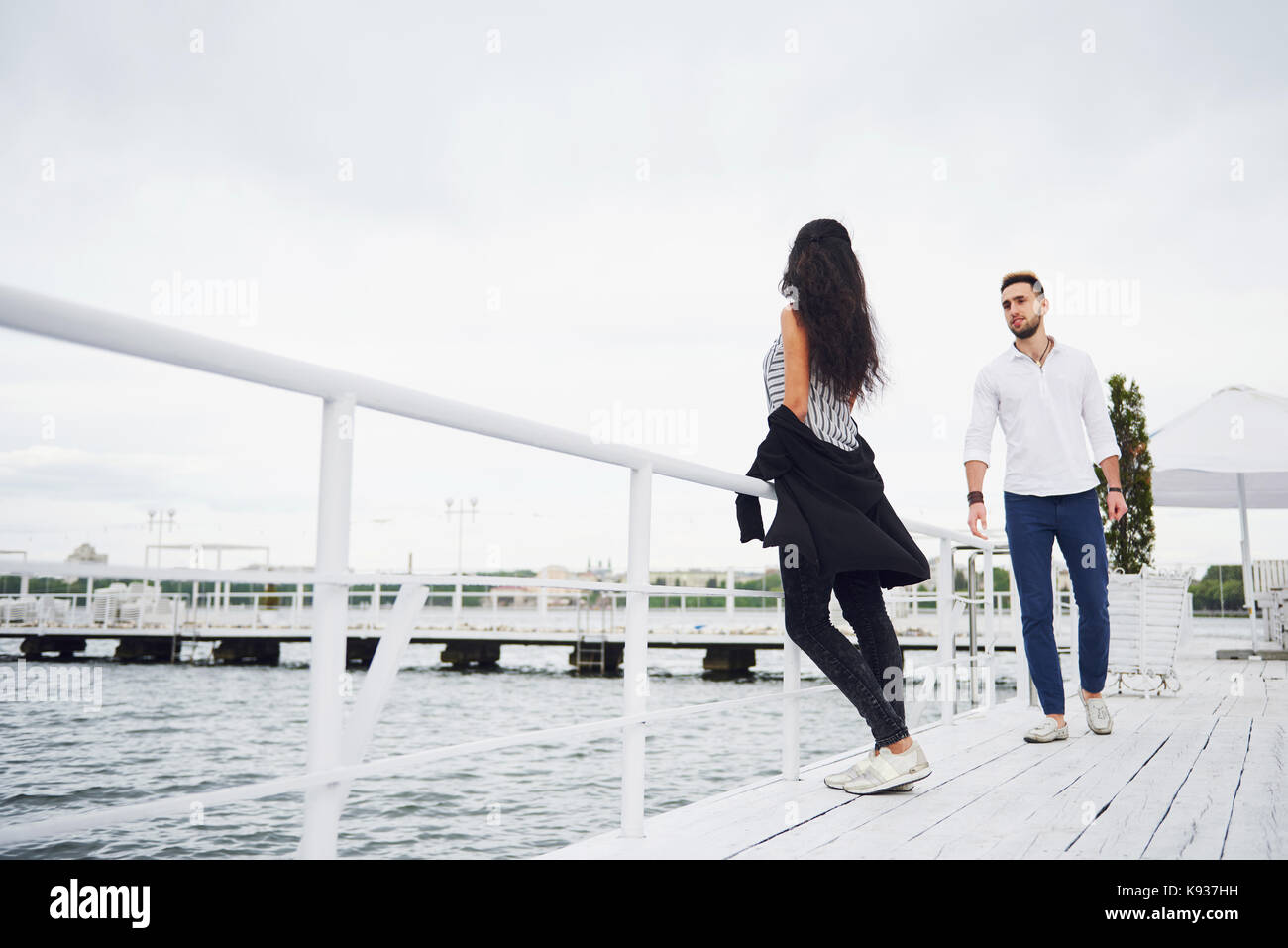 Feliz pareja joven con elegante ropa de marca, de pie en el muelle en el  agua Fotografía de stock - Alamy