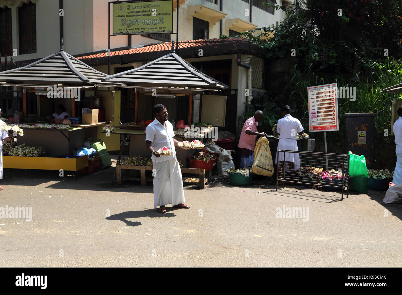 Kandy Sri Lanka hombres vendiendo cuencos de flores de loto como ofrendas en el exterior del templo de la Reliquia del Diente Sagrado Foto de stock