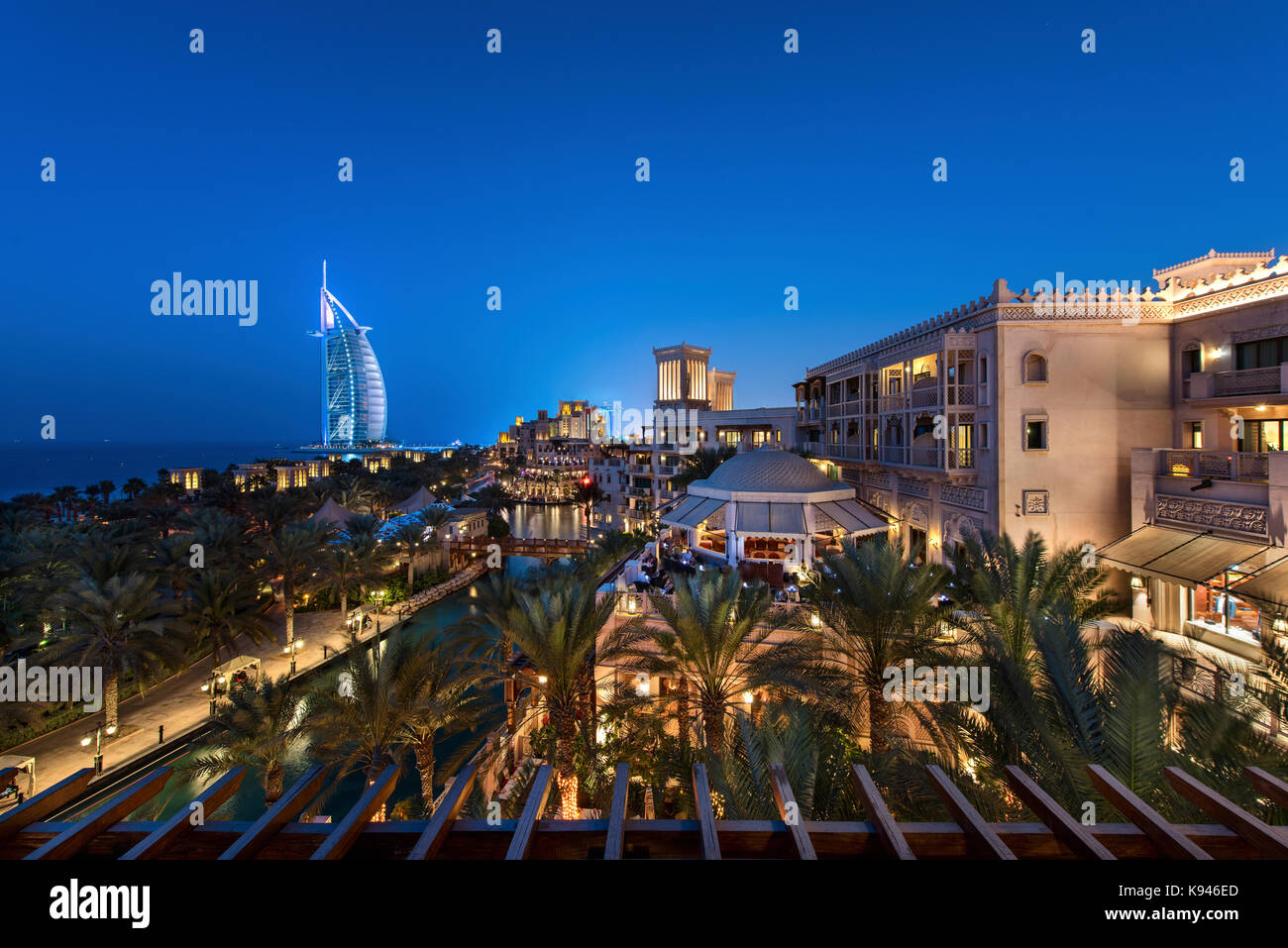 La ciudad de Dubai, Emiratos Árabes Unidos, al atardecer, con edificios iluminados y el burj al arab en la distancia. Foto de stock