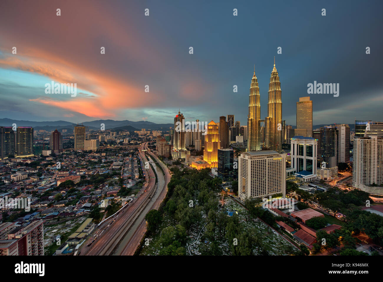 Paisaje urbano de Kuala Lumpur, Malasia, al atardecer, con torres Petronas iluminada en la distancia. Foto de stock