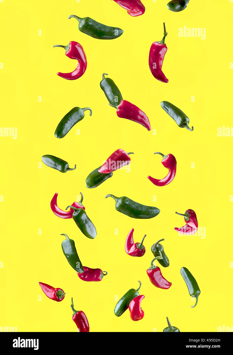 Chiles jalapeños rojos y verdes sobre un fondo amarillo. Foto de stock