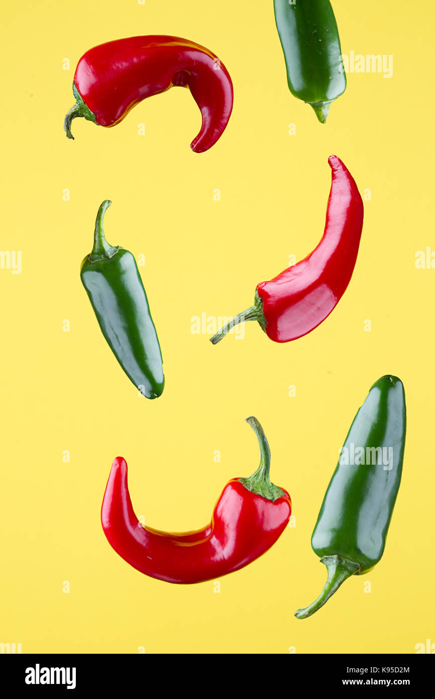 Chiles jalapeños rojos y verdes sobre un fondo amarillo. Foto de stock