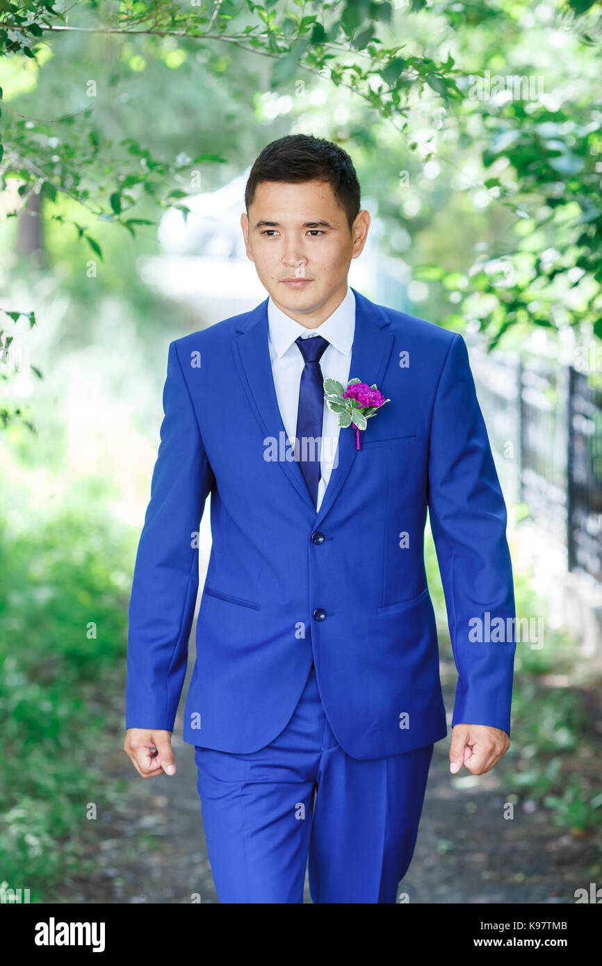 Modelo masculino, el novio retrato en un traje azul con arreglo floral para la del novio entre el follaje verde en un día de boda Fotografía de stock - Alamy