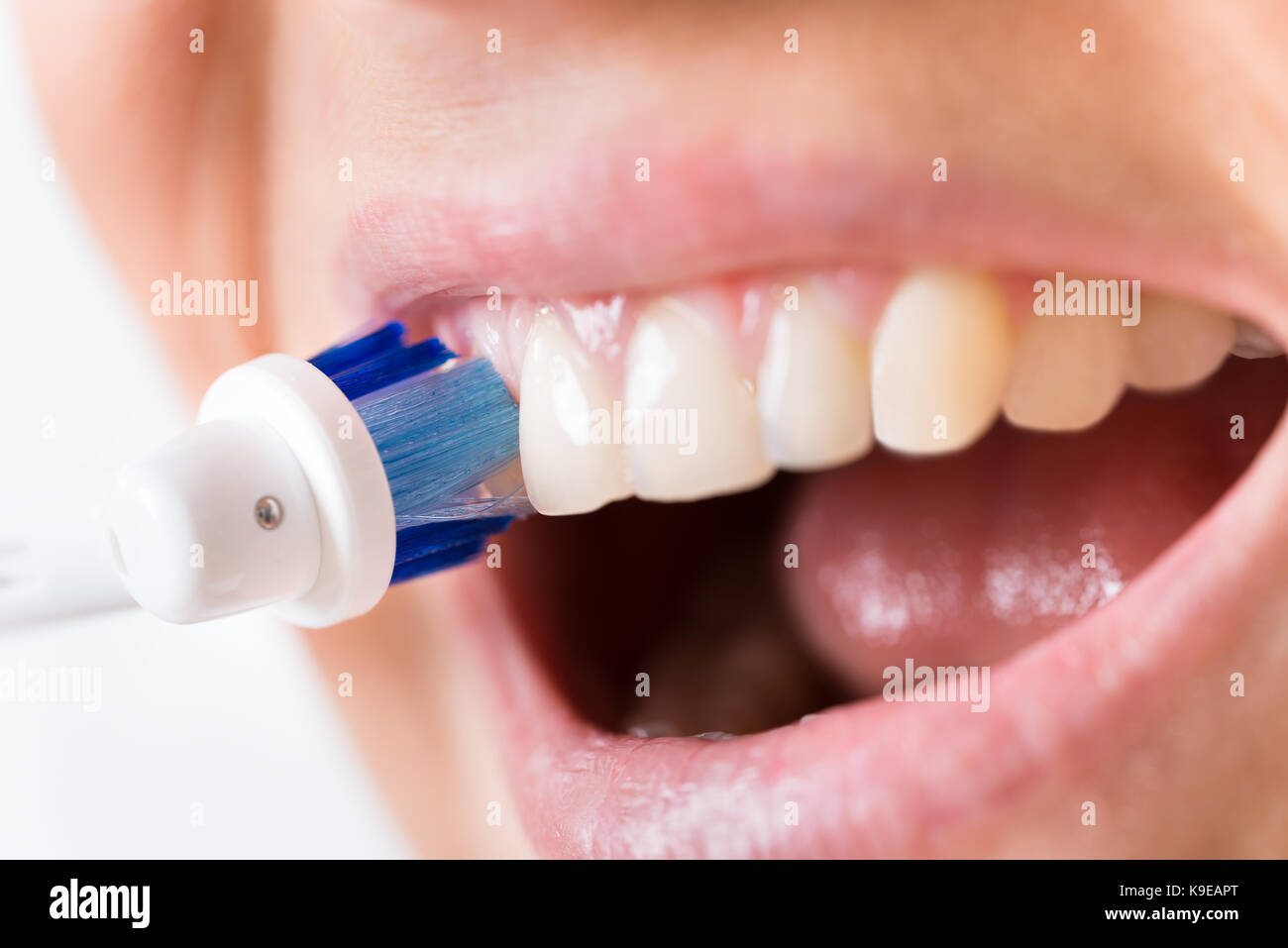 Close-up de una persona cepillarse los dientes con cepillo dental eléctrico Foto de stock