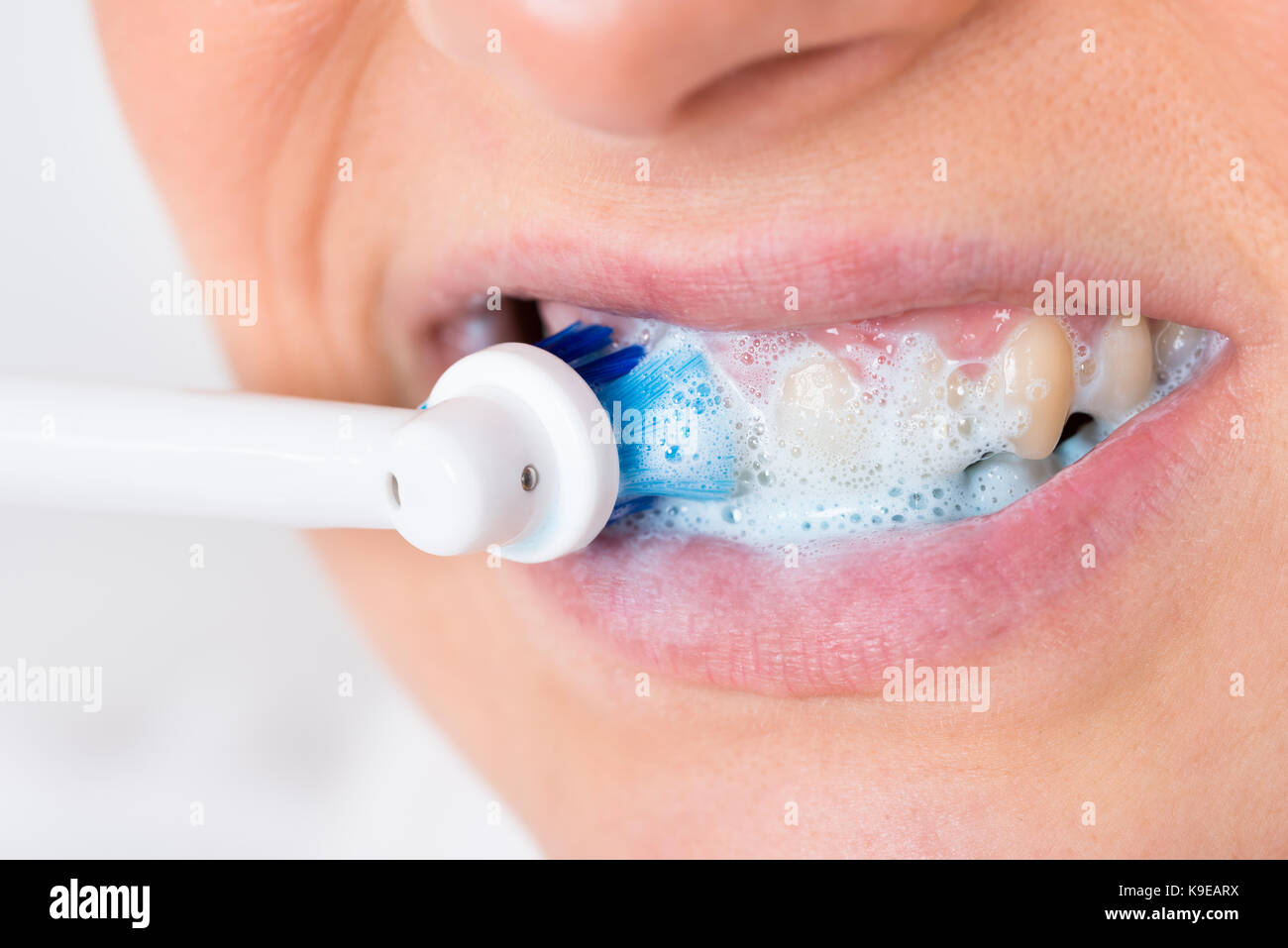 Close-up de una persona cepillarse los dientes con cepillo dental eléctrico Foto de stock