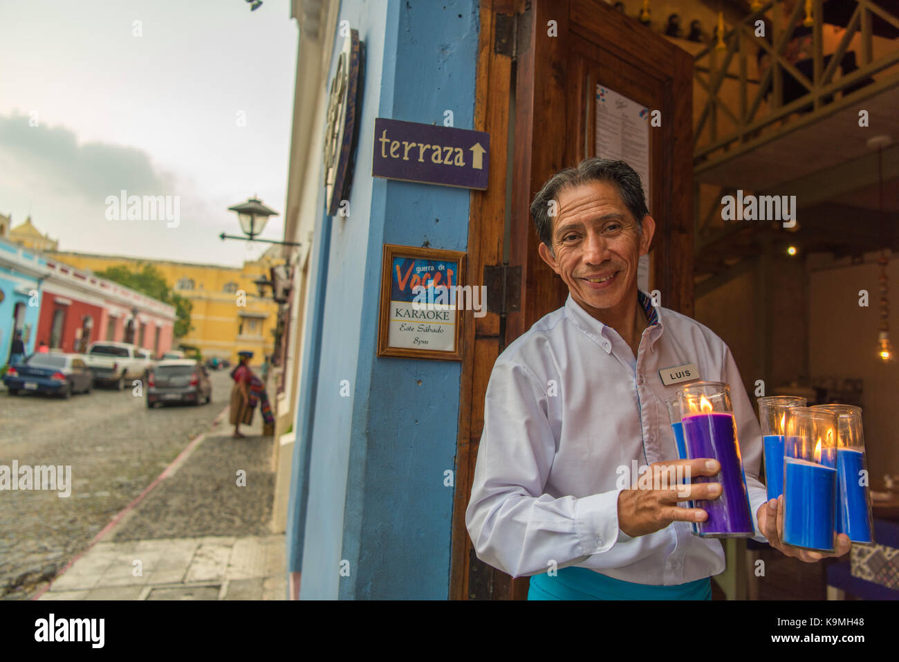 Un camarero comparte una cálida sonrisa mientras prepara su restaurante para los huéspedes de la cena. Antigua, Guatemala Foto de stock