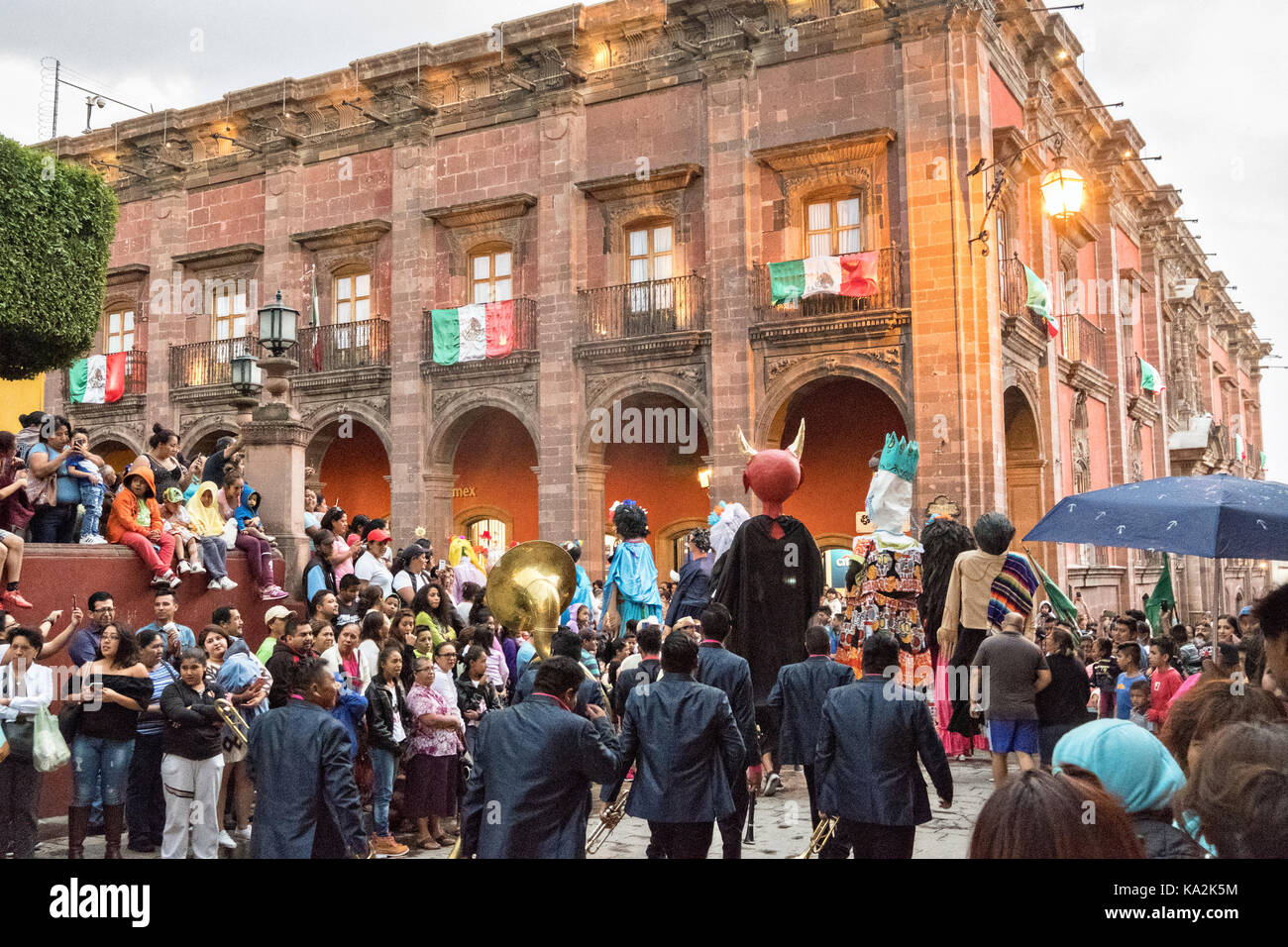 Un Marching Band sigue un desfile de gigantes de papel maché llamados mojigangas títeres en una procesión por la ciudad al comienzo de la semana de la fiesta de la patrona de San Miguel el 22 de septiembre de 2017 en San Miguel de Allende, México. Foto de stock