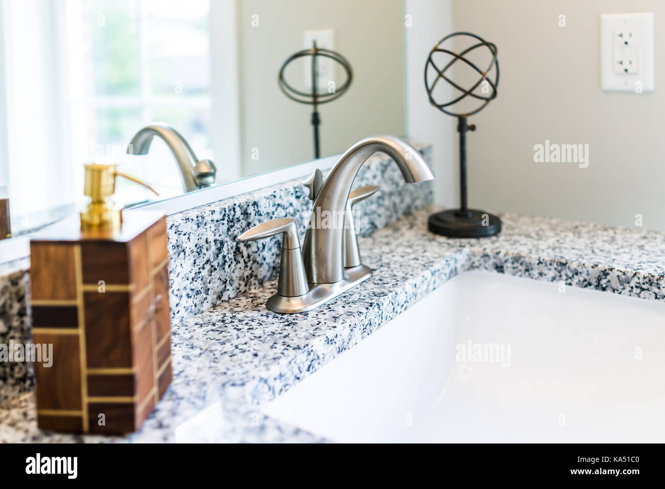 Primer plano de un cuarto de baño moderno lavabo con encimera de granito,  espejo y grifo dispensador de jabón en la estadificación de la casa modelo,  apartamento o casa Fotografía de stock -