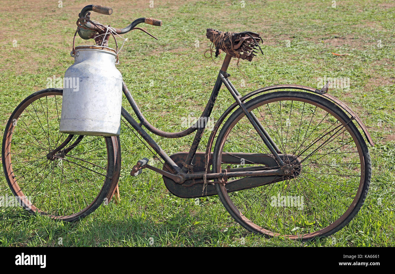 Ordeño muy antigua bicicleta de aluminio con botella de leche para proporcionar leche humedecido Foto de stock