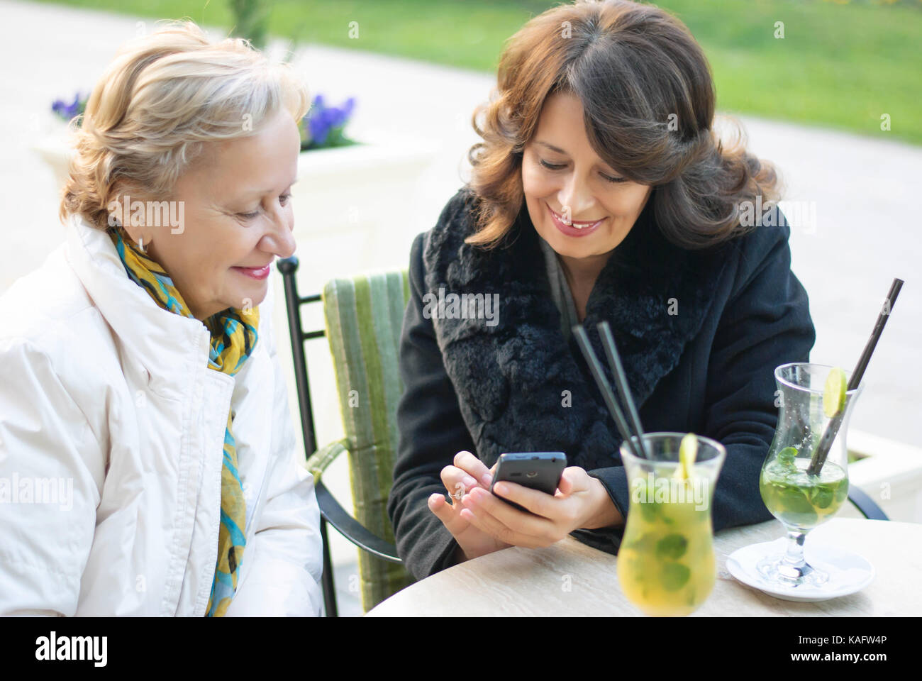 Dos mujeres de mediana edad colgar hacia fuera en el café, después de un soleado día de otoño Foto de stock