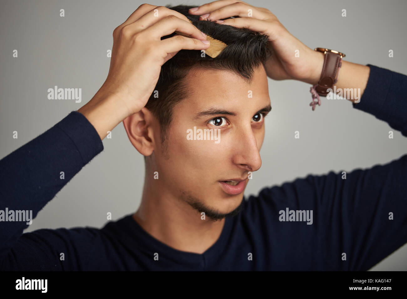Hombre latino haciendo peinado moderno cerrar Foto de stock