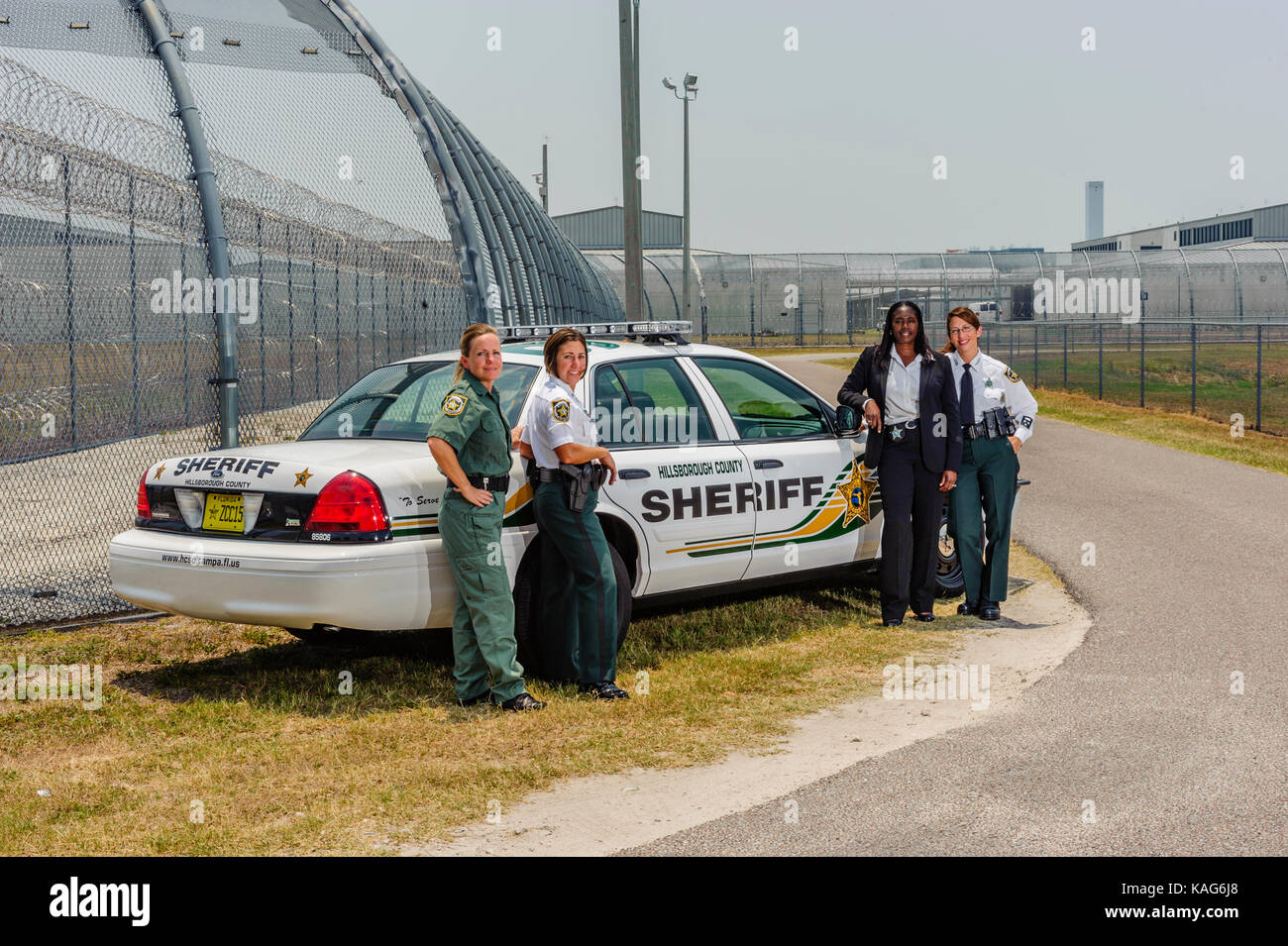 Cuatro diputadas con la Oficina del Sheriff del Condado de Hillsborough de pie delante de un coche patrulla en la cárcel facility en Brandon, Florida USA. Foto de stock
