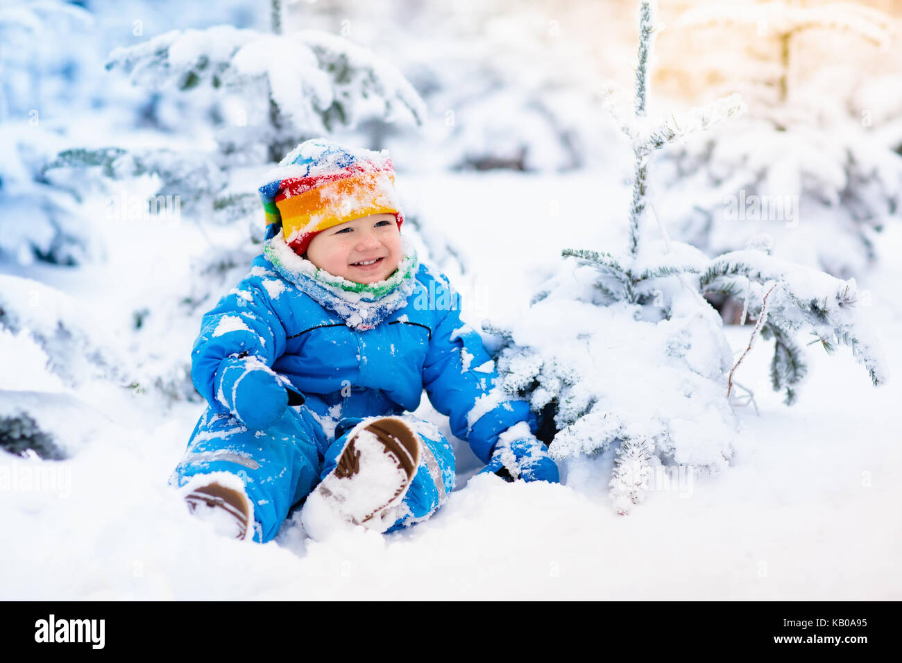 Bebé jugando con nieve en invierno. el pequeño niño chico de azul y sombrero colorido atrapar los de nieve en Winter Park en navidad. Los niños juegan en sno Fotografía
