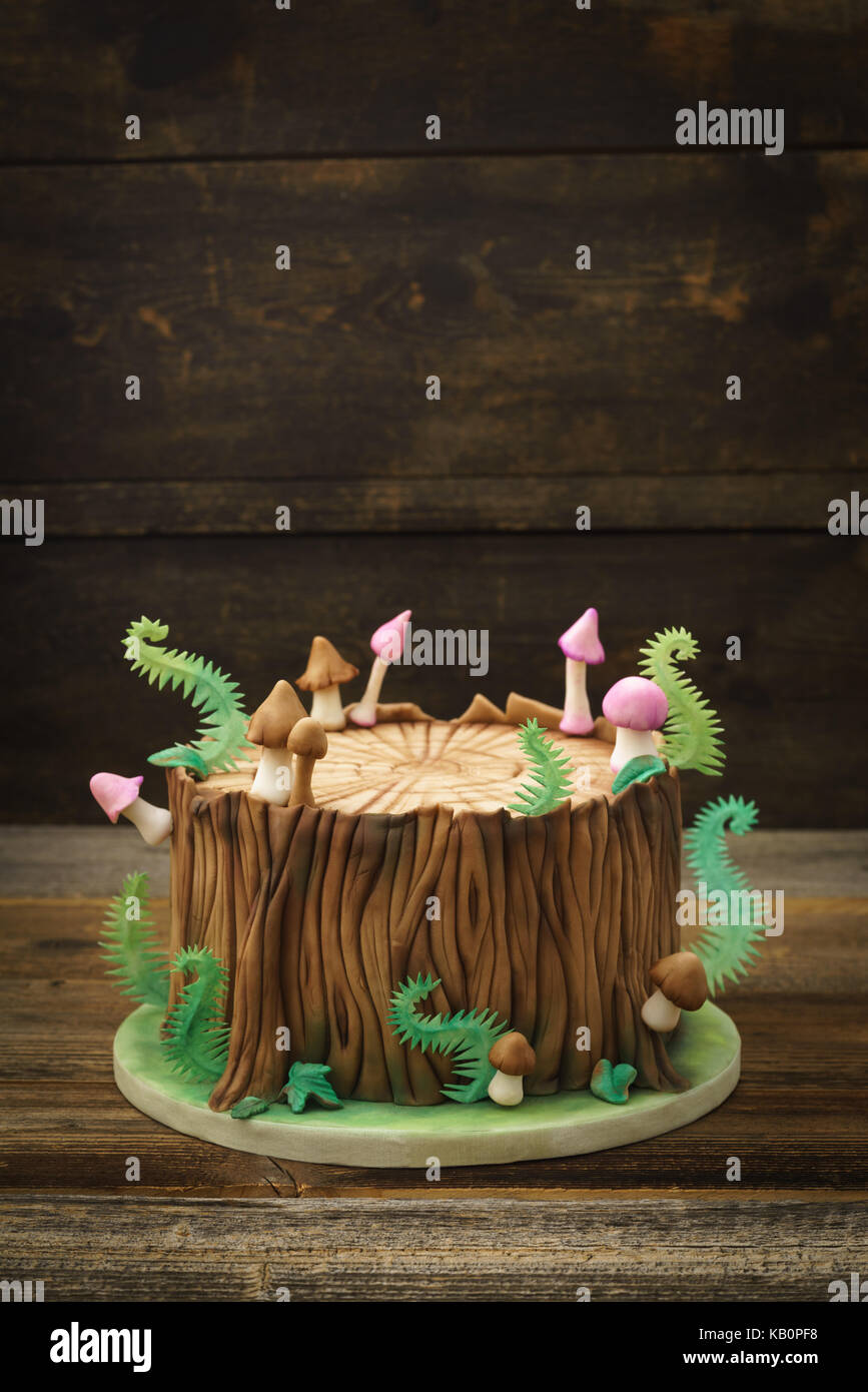 El bosque encantado bosque themed fondant pastel con un tronco de árbol,  helechos, hongos y hojas de madera con fondo copyspace Fotografía de stock  - Alamy
