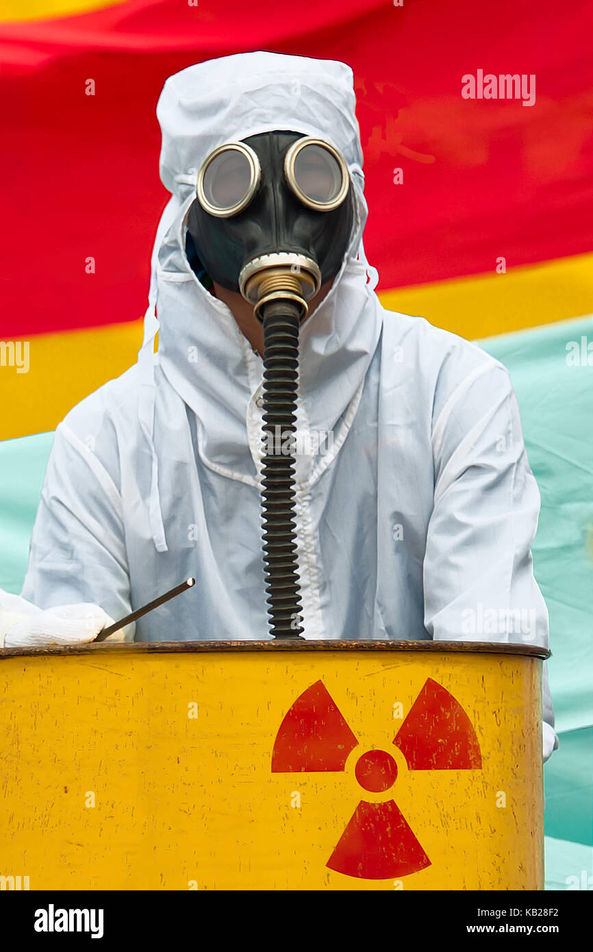 Un hombre en bio-hazard traje y máscara antigás. Un hombre en traje de  riesgo biológico y de pie detrás de una máscara de gas con depósito oxidado  proyectó el símbolo nuclear Fotografía