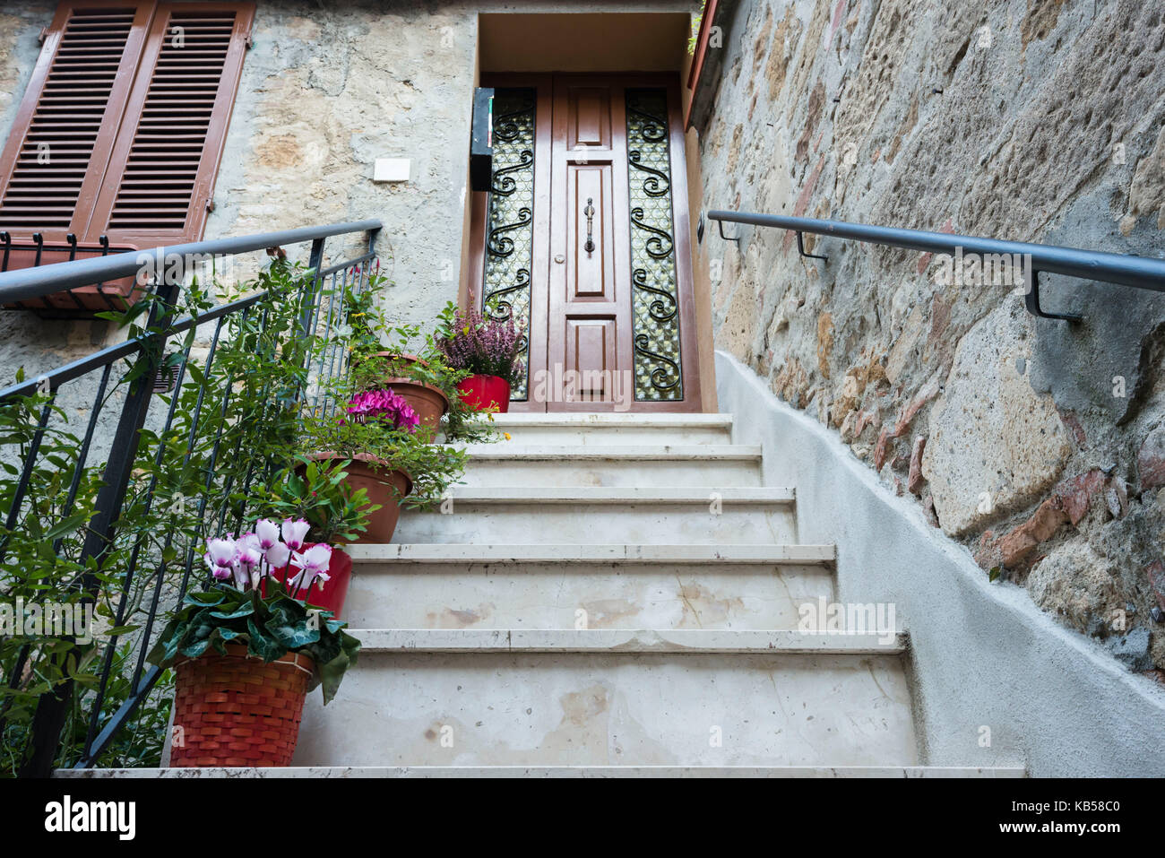 Una perspectiva hacia arriba la escalera a la puerta de la casa de Pienza con un montón de macetas y flores en cada paso Foto de stock