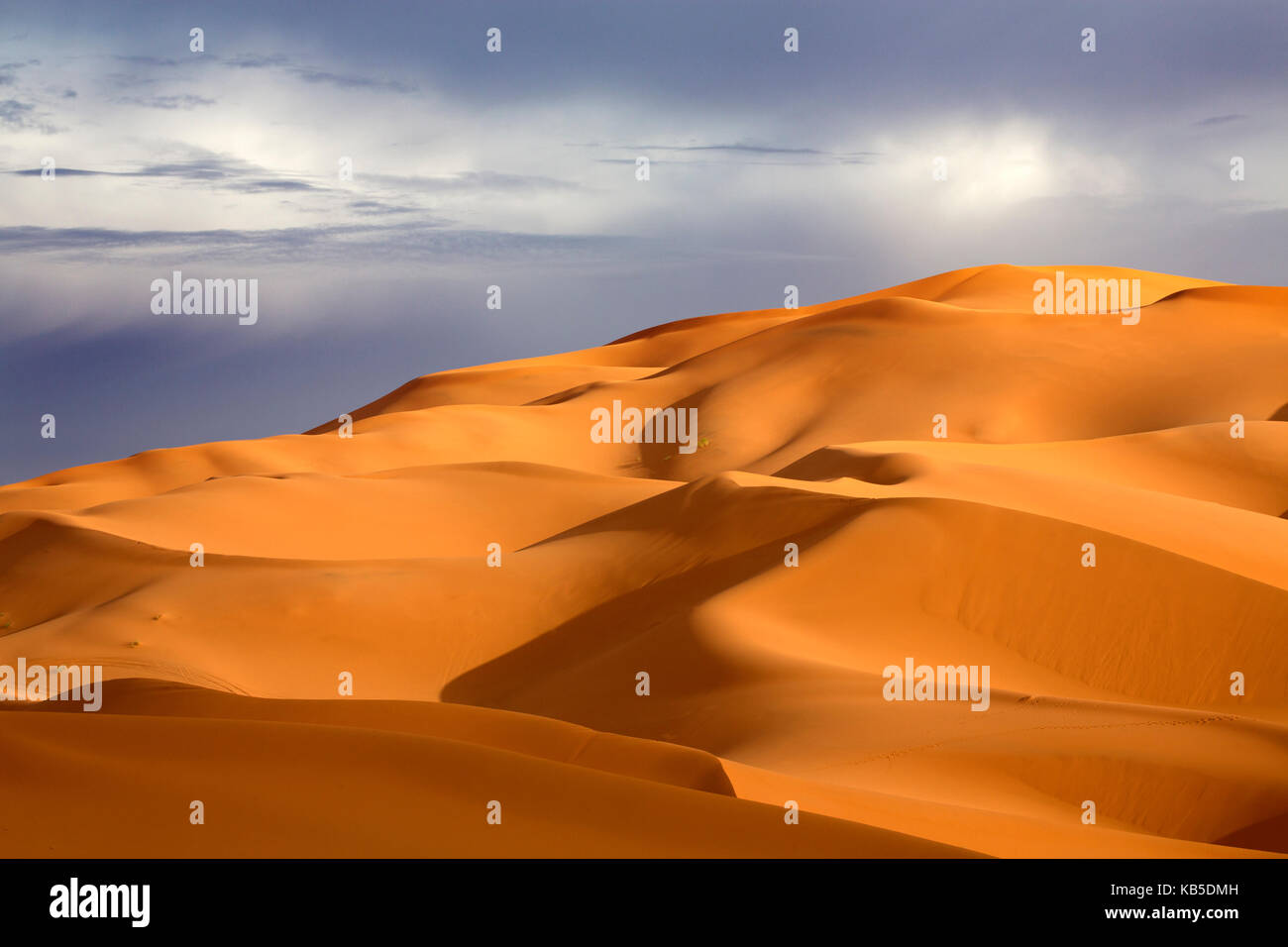 Dunas de arena naranja contra el cielo tormentoso, Erg Chebbi : mar de arena, parte del desierto del Sahara, cerca de Merzouga, Marruecos, Norte de África Foto de stock