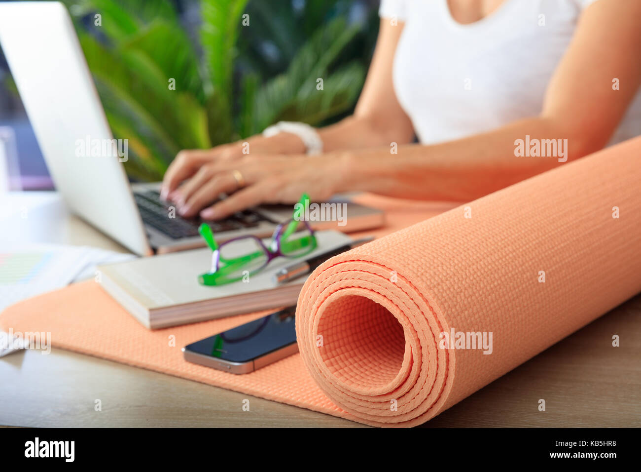 Relájese en el trabajo concepto. estera del yoga en un escritorio de oficina Foto de stock