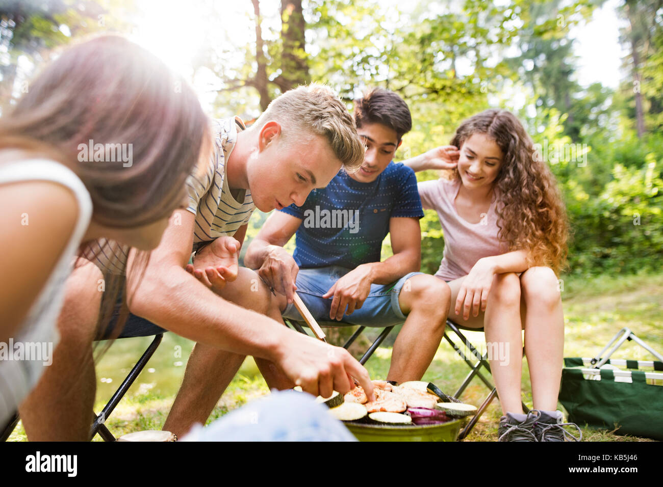 Los adolescentes camping, cocinar las verduras en la parrilla. Foto de stock